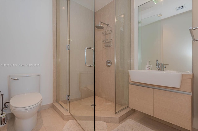 bathroom with tile patterned flooring, vanity, a shower with door, and toilet