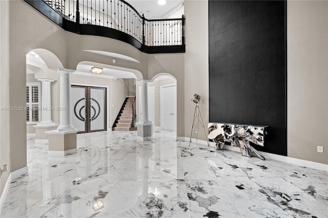 foyer with decorative columns and a high ceiling