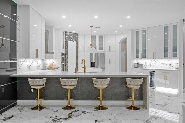 kitchen with sink, a breakfast bar area, appliances with stainless steel finishes, white cabinetry, and beverage cooler