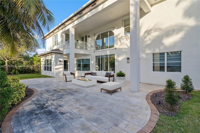 rear view of property with a patio area and an outdoor living space with a fire pit