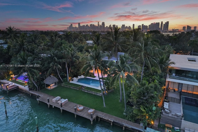 aerial view at dusk featuring a city view and a water view