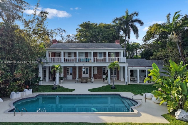 back of house with a chimney, a patio area, a balcony, and french doors