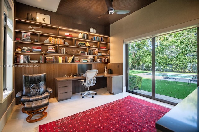 office space with built in shelves, ceiling fan, and built in desk