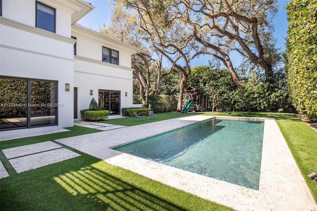 view of pool with a patio, a playground, and a lawn