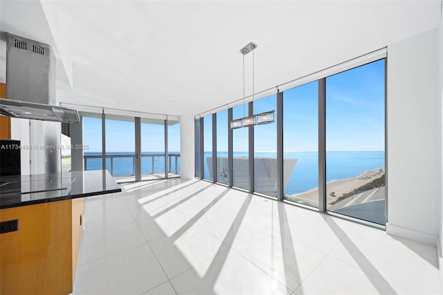 unfurnished living room featuring expansive windows, a water view, and light tile patterned floors