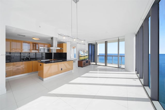 kitchen featuring light tile patterned floors, hanging light fixtures, floor to ceiling windows, tasteful backsplash, and island range hood