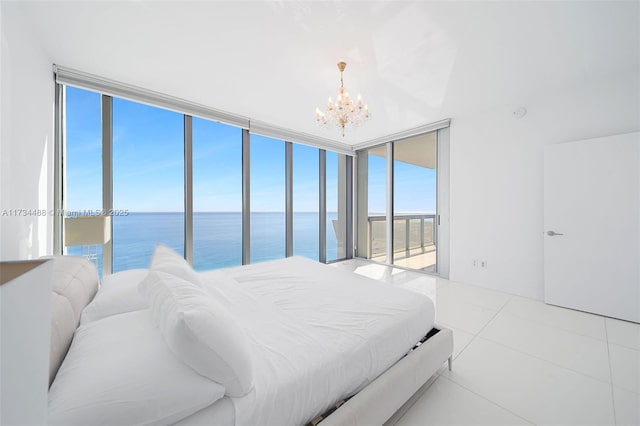 tiled bedroom with access to outside, a water view, and a notable chandelier