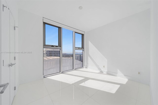spare room featuring a wall of windows and tile patterned floors