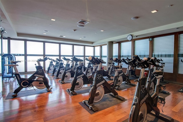 gym with a water view and light hardwood / wood-style floors