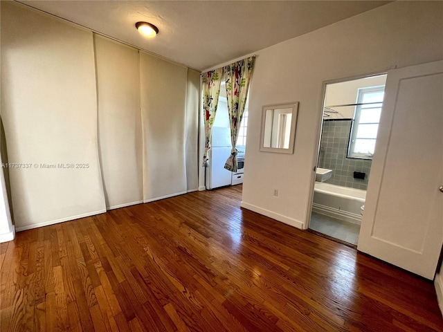 unfurnished bedroom with ensuite bath and dark hardwood / wood-style flooring