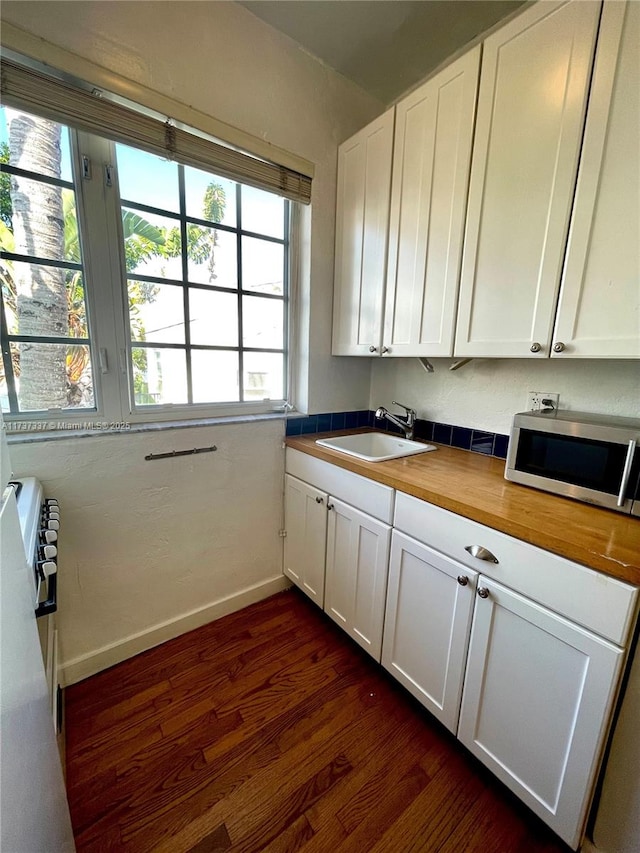 kitchen featuring white cabinetry, sink, dark hardwood / wood-style floors, and butcher block countertops