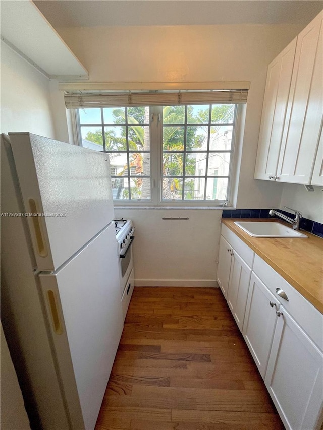 kitchen with sink, white appliances, butcher block counters, white cabinets, and dark hardwood / wood-style flooring