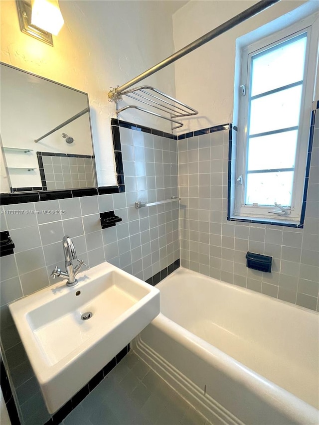 bathroom featuring tiled shower / bath combo, sink, and tile walls