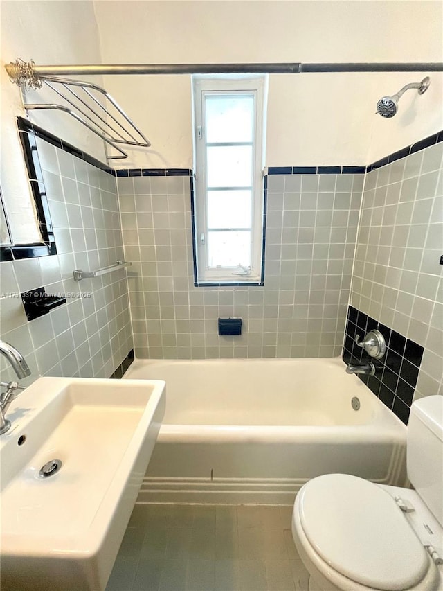 full bathroom featuring toilet, sink, tiled shower / bath, tile walls, and tile patterned flooring