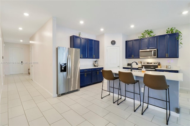 kitchen with blue cabinetry, sink, a kitchen breakfast bar, an island with sink, and stainless steel appliances