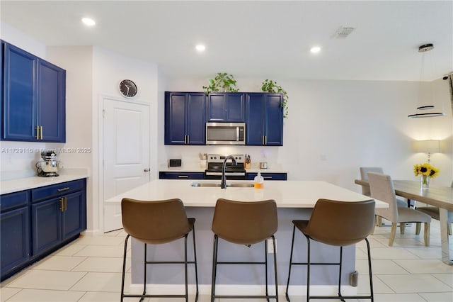 kitchen with sink, a center island with sink, stainless steel appliances, and blue cabinets