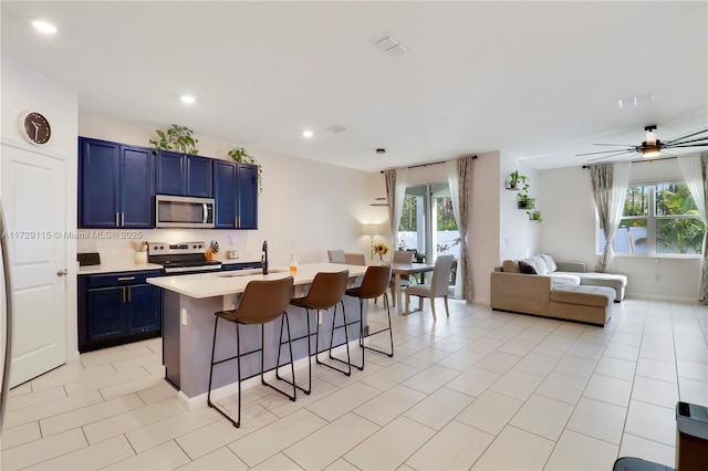 kitchen featuring blue cabinets, an island with sink, sink, a kitchen breakfast bar, and stainless steel appliances