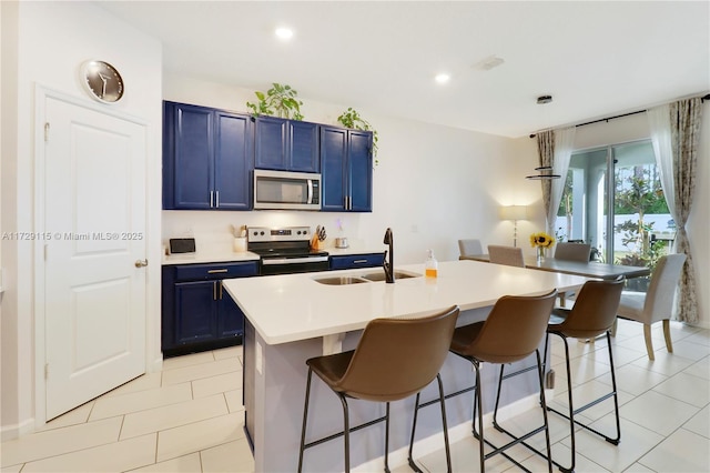 kitchen with blue cabinets, a breakfast bar, sink, a center island with sink, and appliances with stainless steel finishes