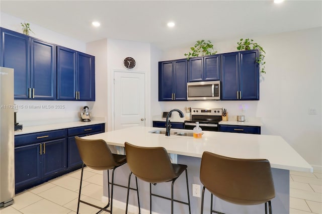 kitchen with blue cabinetry, appliances with stainless steel finishes, a breakfast bar area, and a center island with sink