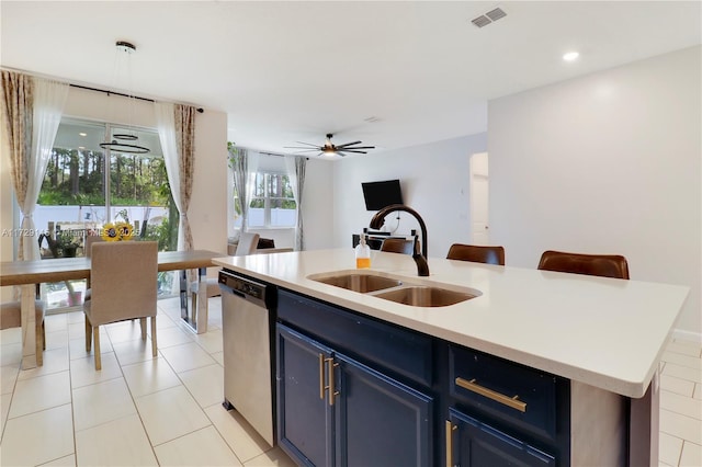 kitchen with sink, light tile patterned floors, blue cabinetry, dishwasher, and a kitchen island with sink