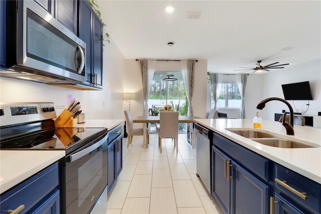 kitchen with blue cabinets, sink, hanging light fixtures, light tile patterned floors, and stainless steel appliances