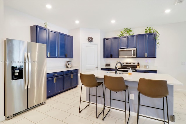 kitchen featuring blue cabinetry, sink, a breakfast bar area, an island with sink, and stainless steel appliances