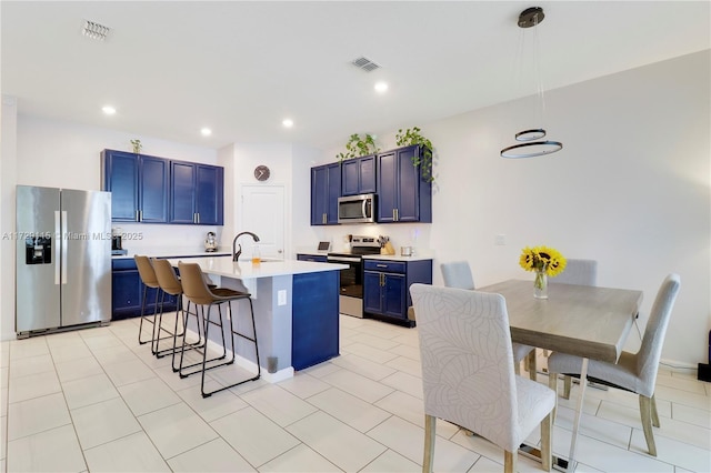 kitchen featuring sink, blue cabinetry, a center island with sink, stainless steel appliances, and a kitchen bar