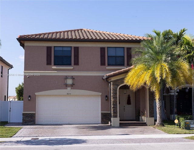 view of front of home featuring a garage, fence, stone siding, driveway, and stucco siding