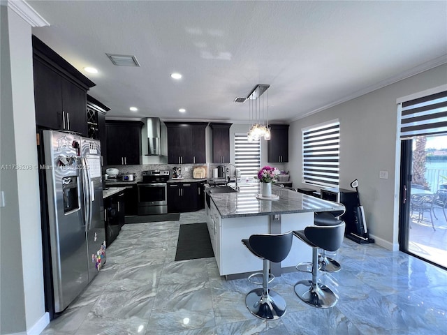 8654 W 33rd Ave, Hialeah, FL 33018 - kitchen featuring appliances with stainless steel finishes, dark cabinets, wall chimney exhaust hood, decorative backsplash, and a kitchen island with sink