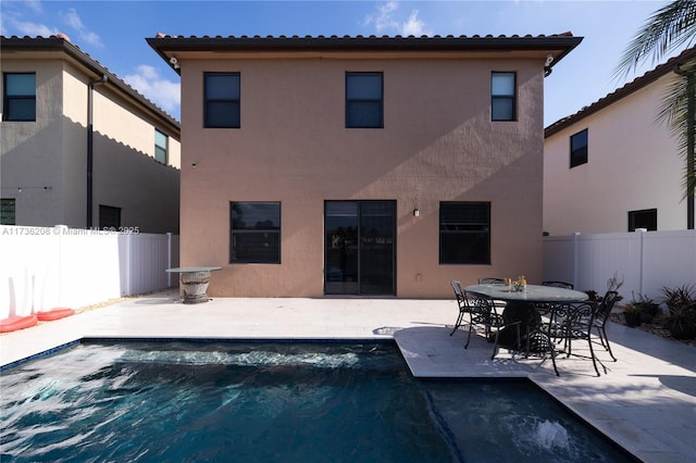 rear view of property featuring a fenced in pool and a patio