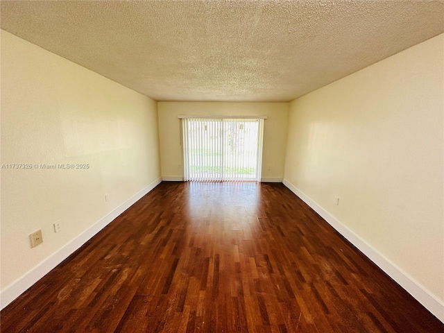 spare room featuring dark wood-type flooring and a textured ceiling