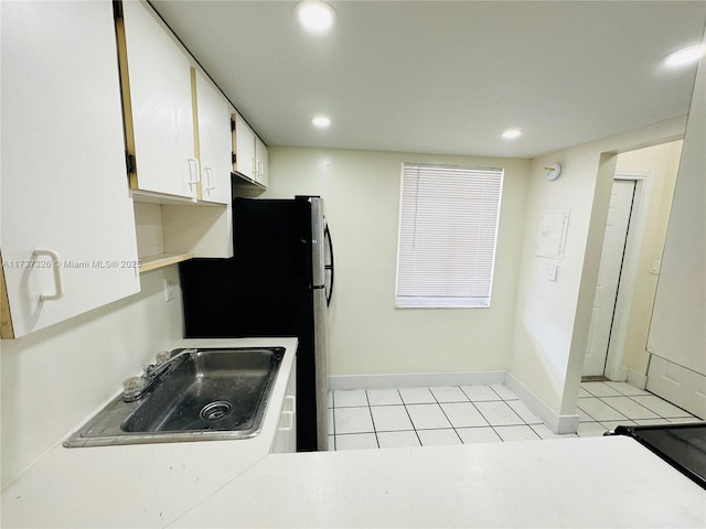 kitchen featuring white cabinetry, sink, light tile patterned floors, and stainless steel fridge