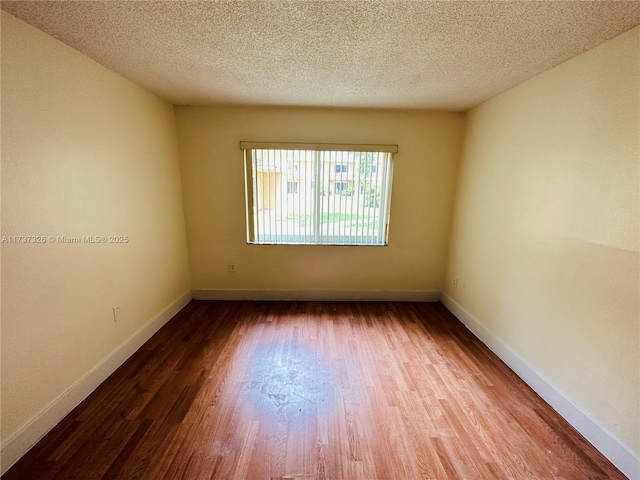 unfurnished room with hardwood / wood-style floors and a textured ceiling