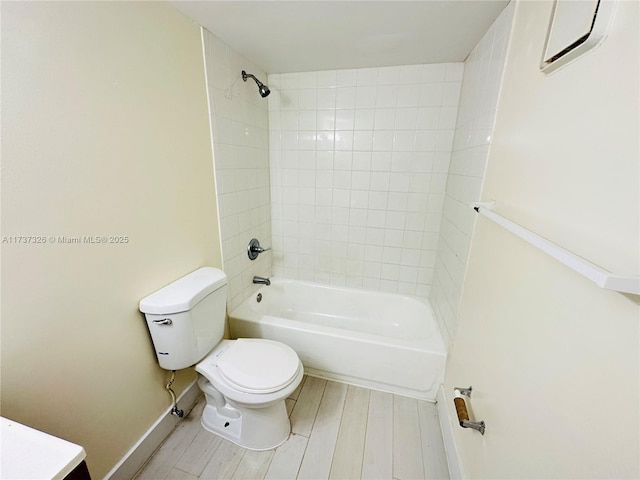 full bathroom featuring vanity, hardwood / wood-style floors, tiled shower / bath combo, and toilet