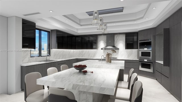 kitchen featuring sink, backsplash, a center island, a raised ceiling, and wall chimney exhaust hood