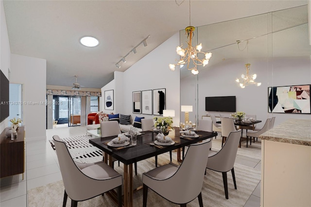 tiled dining space with high vaulted ceiling, rail lighting, and a chandelier