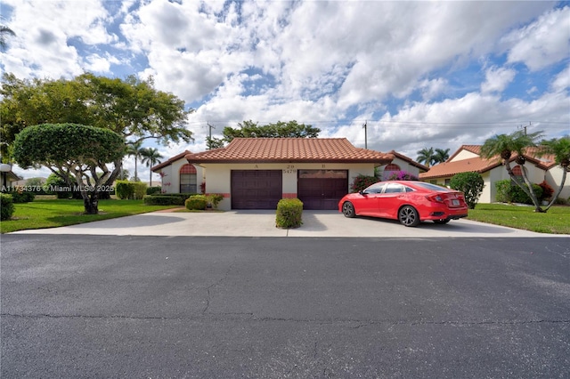 mediterranean / spanish house featuring a garage and a front lawn