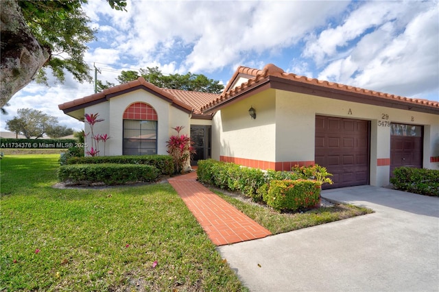 mediterranean / spanish house featuring a garage and a front lawn