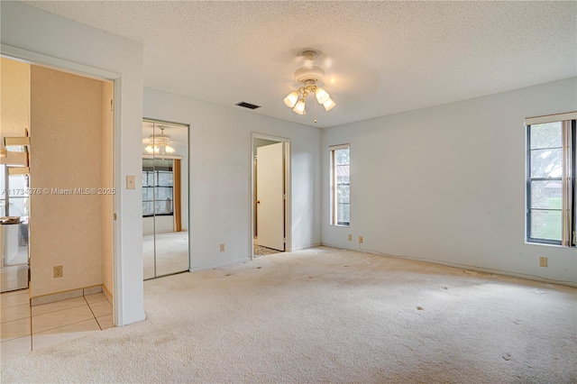 unfurnished bedroom with ceiling fan, light colored carpet, and a textured ceiling