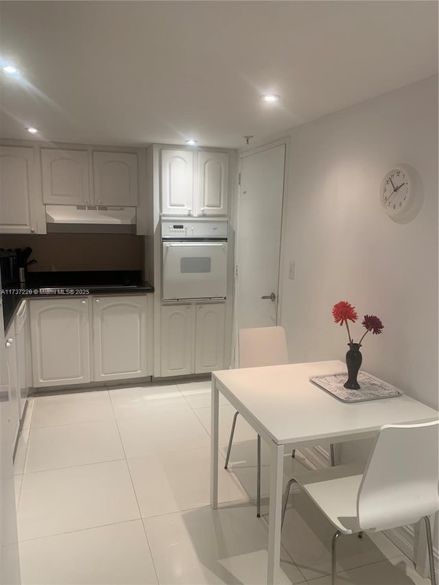 kitchen featuring white cabinetry, light tile patterned floors, a kitchen breakfast bar, and white oven