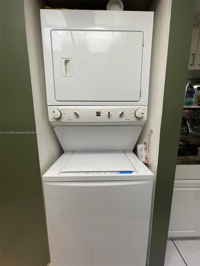 clothes washing area with stacked washer / drying machine and sink