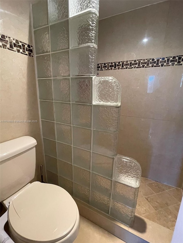 bathroom featuring toilet and tile walls