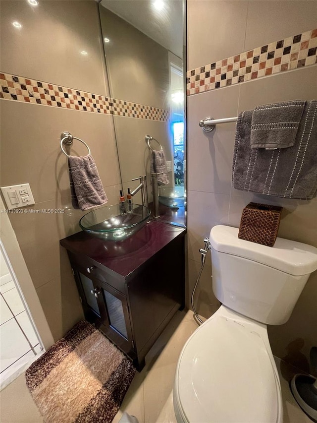 bathroom featuring vanity, toilet, and tile walls