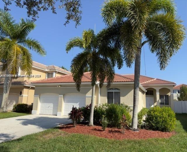 mediterranean / spanish-style home with a garage and a front lawn