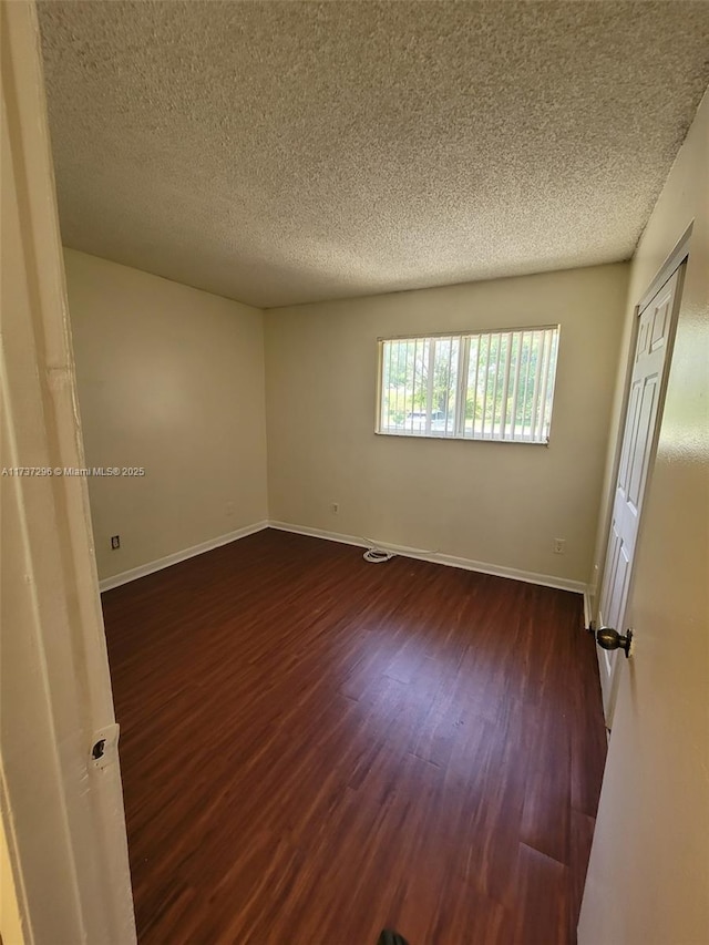 spare room featuring dark hardwood / wood-style flooring and a textured ceiling