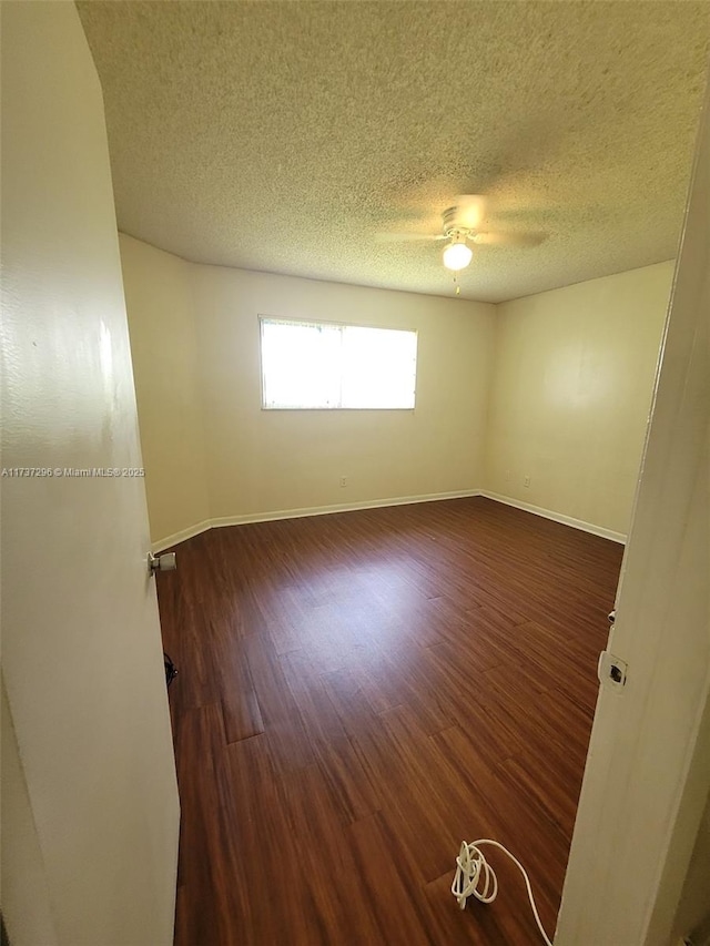 spare room with ceiling fan, dark wood-type flooring, and a textured ceiling