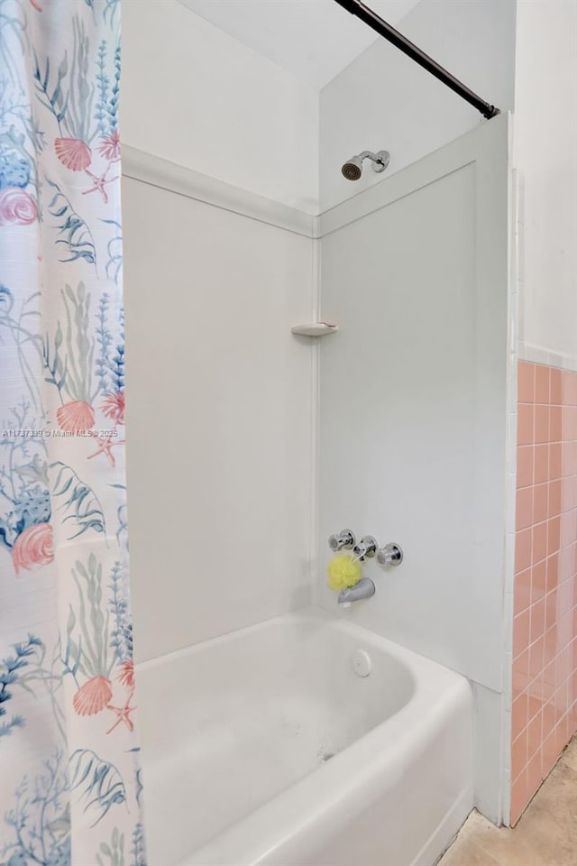 bathroom with tile walls and shower / bath combo with shower curtain