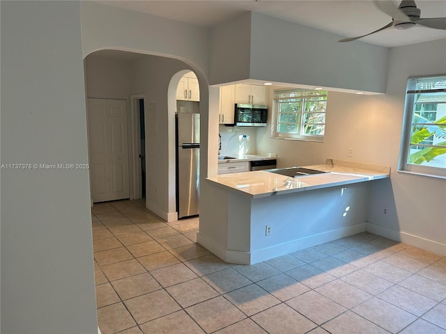 359 Meridian Ave Unit A207, Miami Beach, FL 33139 - kitchen featuring appliances with stainless steel finishes, white cabinets, arched walkways, and light tile patterned flooring