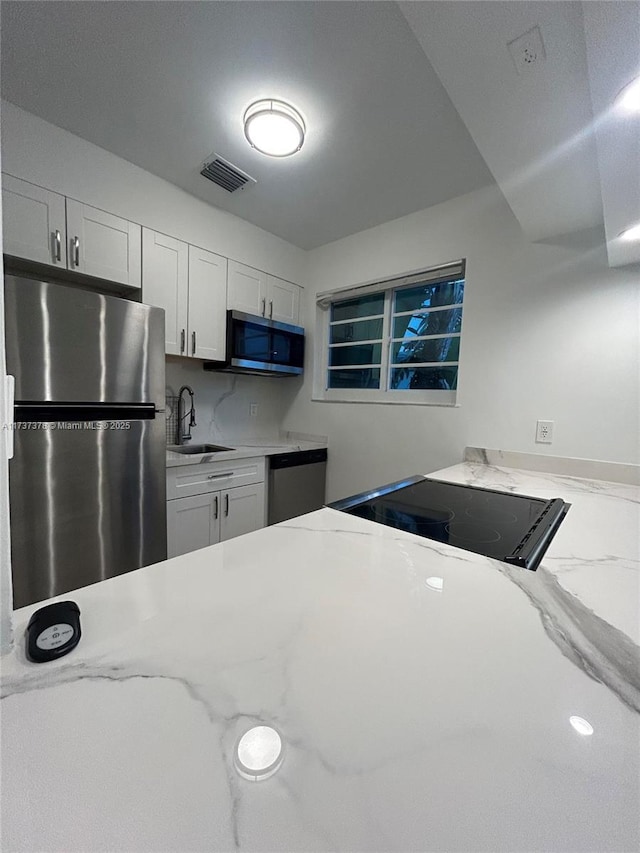 359 Meridian Ave Unit A207, Miami Beach, FL 33139 - kitchen featuring stainless steel appliances, white cabinetry, and light stone counters
