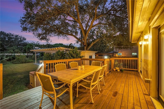 deck at dusk featuring a yard and a pergola